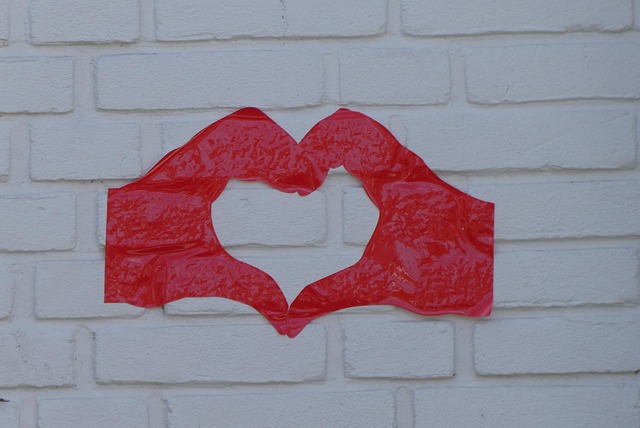 A creative display of red tape forming a heart shape against a white brick wall.