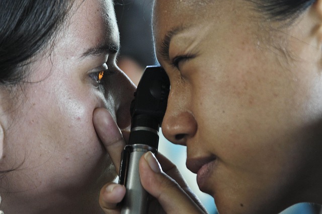 A healthcare professional using an otoscope to examine a patient's eye, showcasing a close interaction during a medical check-up.